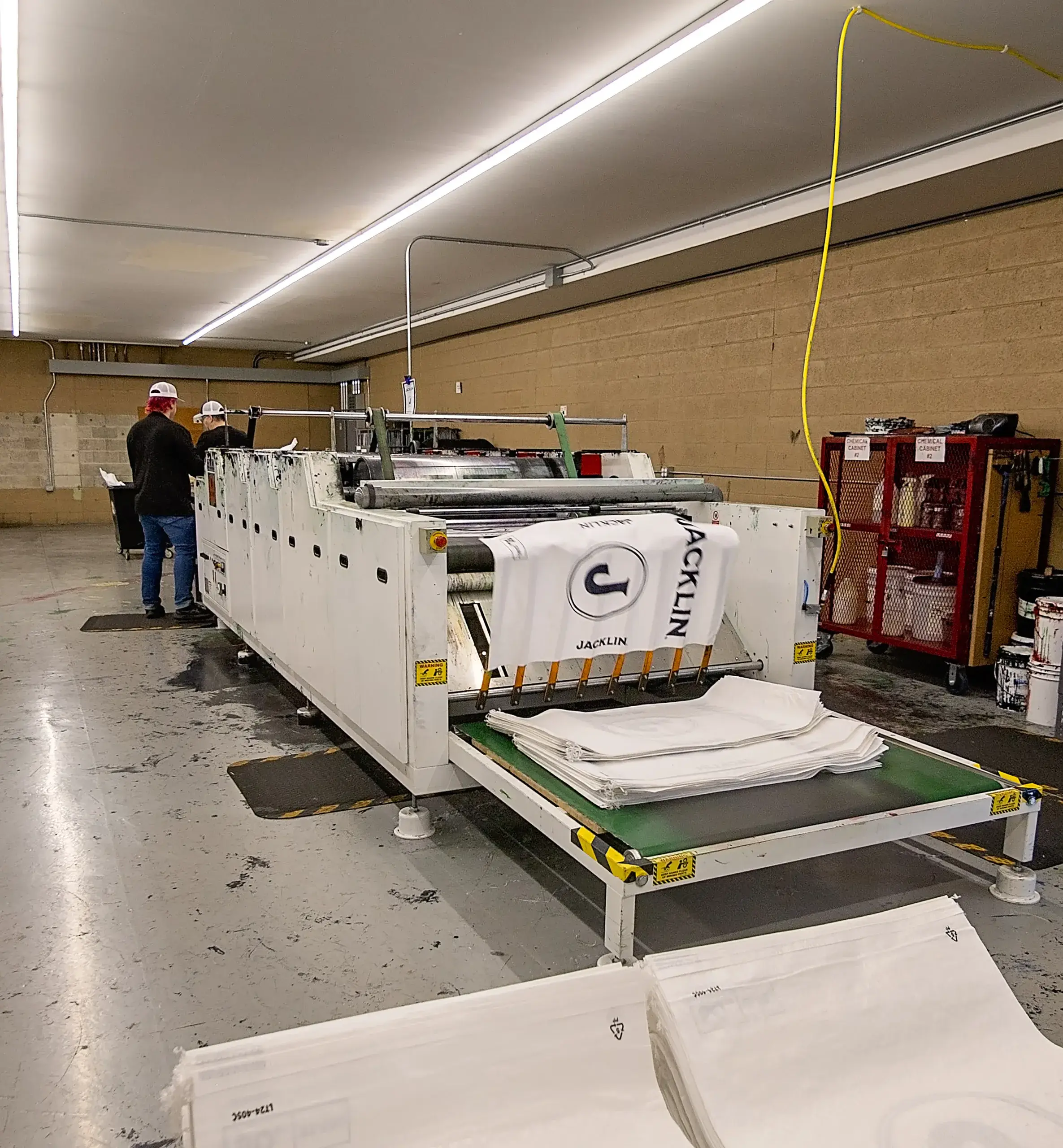 Employees standing at a bag printing press